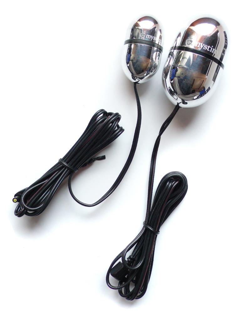 A small and large Mystim Egg-Cellent Egon are displayed next to each other against a blank background. They are silver alumnium eggs with a long black cord connected to the bottom.