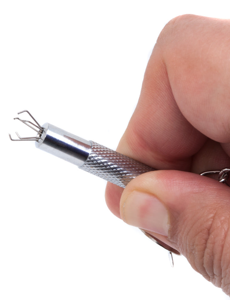 Someone holds an Extreme Talon Nipple Clamp against a blank background, showing a close-up of the exposed claws. The claws, made of five small, metal claws that branch outwards and are bent inwards at a 90-degree angle, emerge from the tip of the clamp.