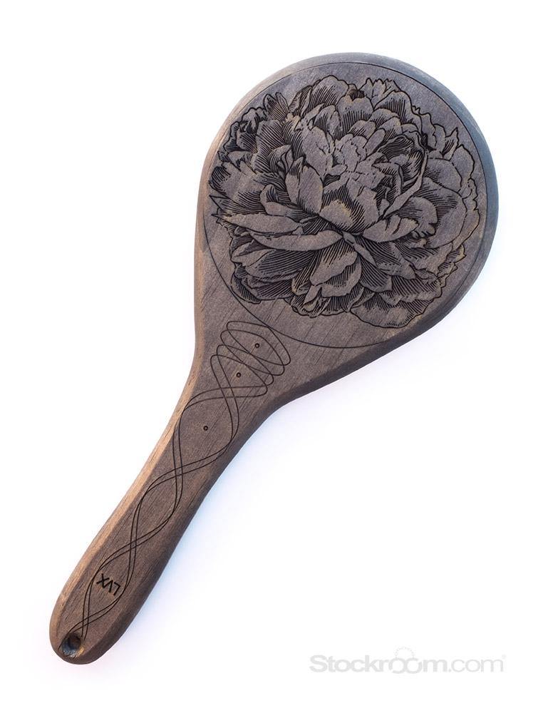 The Ebony Pine Peony Engraved Wooden Spanking Paddle, a dark wood ping-pong style panel with a detailed peony engraved on it, is displayed against a blank background.