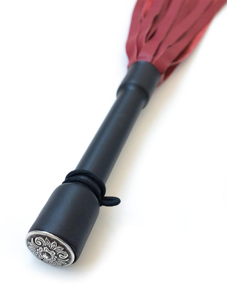 A close-up of the Red Devil Leather Flogger By Dragontailz handle is displayed against a blank background, showing the silver ornamental cap on the end of the handle. 