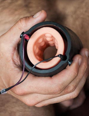 A close-up shows a man holding the Electrastim "Jack Socket" Electro Stroker near his penis with two wires plugged into the top of the stroker.