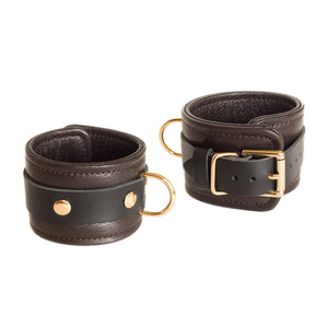 The Brown Leather Wrist Restraints With Gold Accent Hardware are shown against a blank background.