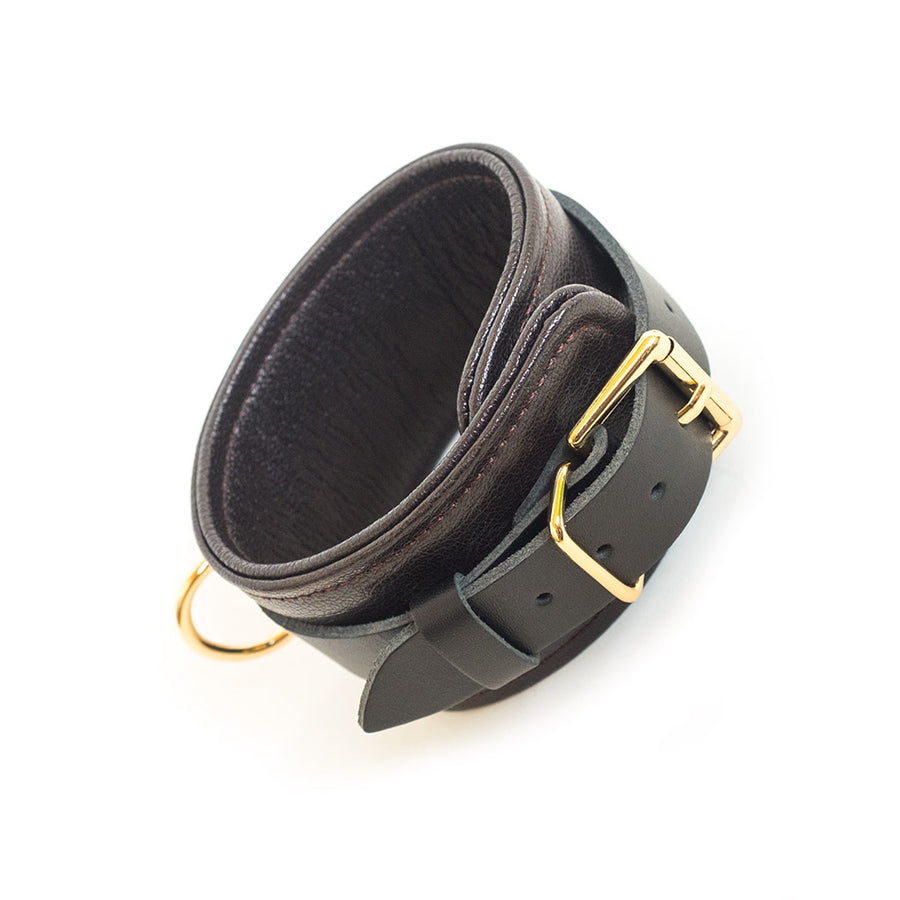 One of the Brown Leather AnkleRestraints With Gold Accent Hardware is shown against a blank background, displaying the cuff’s buckle.