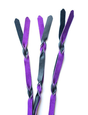 A close-up of the falls on the purple and black Braided Leather Flogger is displayed against a blank background.