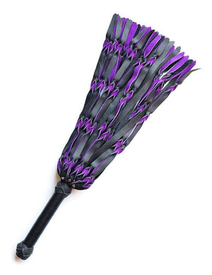The purple and black Braided Leather Flogger is displayed against a blank background. The flogger’s falls are made of strips of black and purple leather braided together. The handle is long and cylindrical with knots of braided leather and both ends.