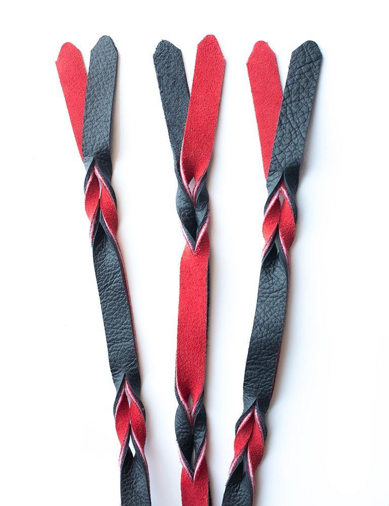 A close-up of the falls on the red and black Braided Leather Flogger is displayed against a blank background.