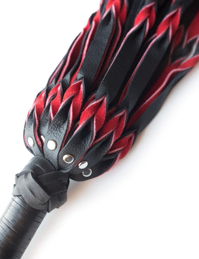 A close-up of the top of the red and black Braided Leather Flogger handle is displayed against a blank background.