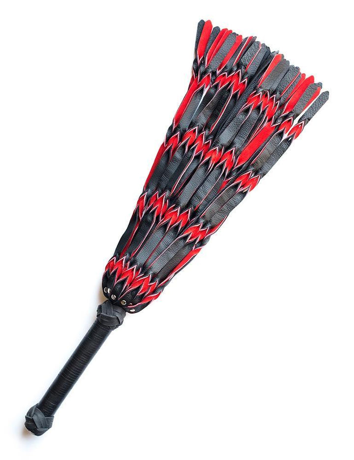 The red and black Braided Leather Flogger is displayed against a blank background. The flogger’s falls are made of strips of black and red leather braided together. The handle is long and cylindrical with knots of braided leather and both ends.