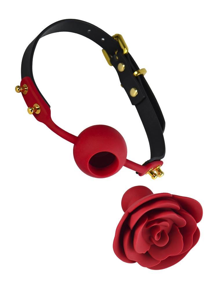 The Rose Ball Gag is displayed taken apart against a blank background. The gag has a leather strap with gold hardware and a red silicone ball in the center with a hole. A red silicone rose with a plug in the back is in front of the gag.