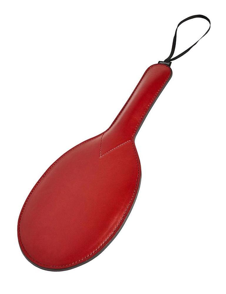The Saffron Ping Pong Paddle, made of red vegan leather with a black wrist loop on the handle, is displayed against a blank background.