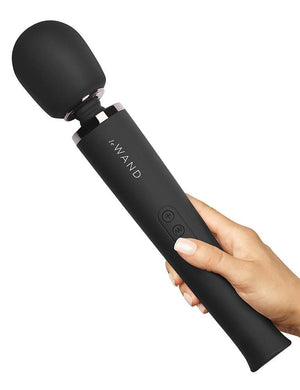 A hand is holding a Le Wand Rechargeable Vibrating Massager in Black against a blank background.