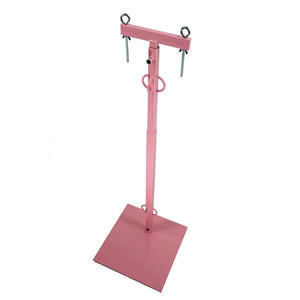 The Cock And Ball CBT Pillory is shown in pink against a blank background. It has a square base with a long pole emerging from it and twp adjustable metal clamp bars on the top. The pole has 6 restraint points, 3 for the wrists and 3 for the ankles.