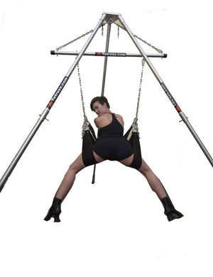  The Tetruss Portable Dungeon Deluxe Bundle is shown in use against a blank background. A woman is shown from the back, leaning forward against one of the stirrups while her legs are supported by the others, all of which are attached to the spreader bar.