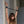 Load image into Gallery viewer, A woman with brown hair is shown from the chest up, standing in front of a concrete wall. Her arms are raised above her head and spread apart with the black Wrist Spreader Bar with Leather Cuffs.
