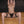 Load image into Gallery viewer, A topless woman with dark hair wearing black underwear sits on a wooden floor, leaning back against a couch. Her arms are raised above her head and her legs are spread apart with the black Thigh Spreader Bar.
