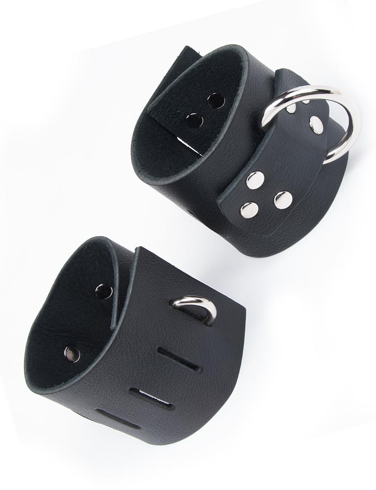 The Extra Wide Black Leather BDSM Wrist Cuffs are shown against a blank background. They are made of a wide piece of black leather and metal hardware, including a D-ring. The cuffs have multiple notches on them and a hasp closure. 