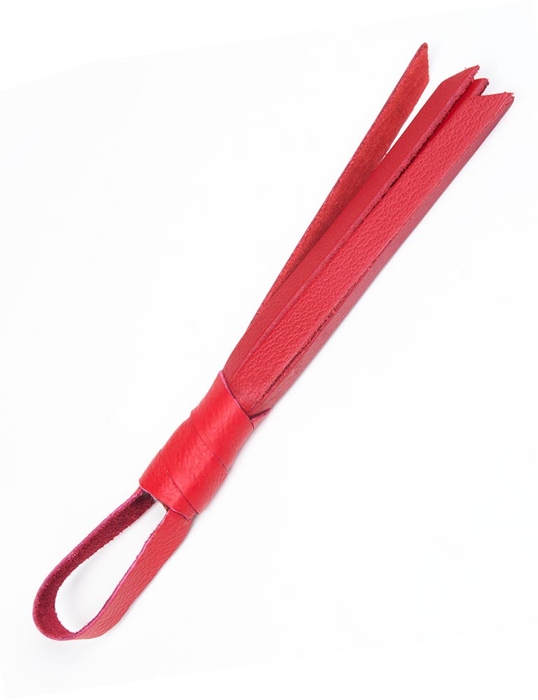 The red Teeny Weeny Leather Flogger from The Stockroom is shown against a blank background. It is a mini flogger made of red leather with a tiny handle and loop at the end.