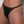 Load image into Gallery viewer, A close-up of a woman&#39;s groin area is shown in front of a white wall. She wears the Women&#39;s black Leather Thong. The thong itself is made of black leather, and the hip bands are made of thin pieces of black elastic.
