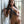 Load image into Gallery viewer, A nude brunette woman poses in a doorway, leaning against the door frame. She holds the handle of the 18-inch Basic Leather BDSM Flogger in one hand and some of the falls in the other.
