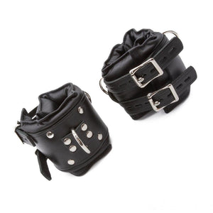 The Premium Lockable Dungeon BDSM Leather Ankle Cuffs are shown against a blank background. They are made of black leather with silver hardware. The cuffs are wide and padded. They have a D-ring and two adjustable straps with lockable buckles.