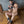 Load image into Gallery viewer, A nude, muscular, brunette man sits on a wooden floor, leaning against a metal wall. He wears the Premium Lockable Dungeon Ankle Cuffs and matching wrist cuffs, which are clipped together with a snap hook. He also wears a black leather posture collar.
