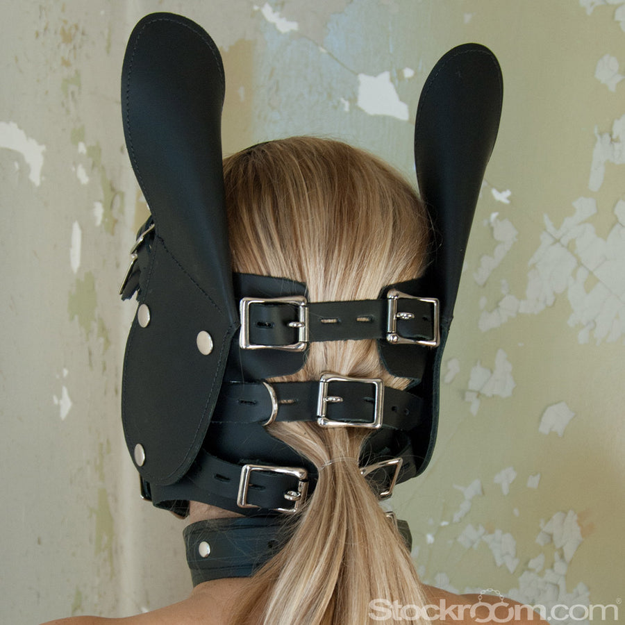 The back of a blonde woman's head in the Leather Pony Head Bridle Set is shown. The hood has four adjustable straps that buckle across the back of her head and neck. The buckles are made of silver metal and are lockable.