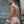 Load image into Gallery viewer, A brunette man is shown from behind, standing outdoors in front of a metal wall and wearing the leather Tightie-Whitey Jockstrap. He also wears a white leather collar and matching wrist cuffs.
