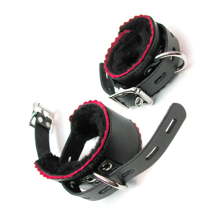 A pair of Fleece Lined Leather Wrist Cuffs With Red Scalloped Edges are displayed against a blank background. They are black leather with red scalloped edges and black fleece lining. They have silver D-rings and lockable buckle closures.