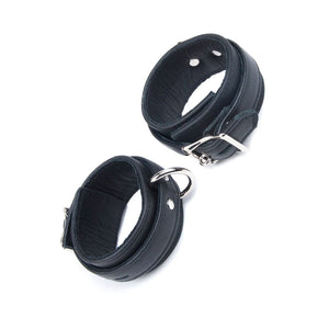 A pair of black Premium Garment Leather Ankle Cuffs are displayed against a blank background. They are made of black leather with silver hardware. Each cuff has one D-ring, and they fasten with lockable buckles.