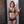 Load image into Gallery viewer, A pink-haired woman in black lingerie stands in front of a white wall. She is holding the red Premium Garment Leather Leash, which is attached to her matching collar. She also wears matching wrist cuffs.
