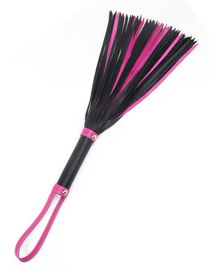 The Joanna Angel Flogger is shown against a blank background. The flogger has a mixture of black and hot pink falls. The handle is black leather with pink accents and a pink leather wrist loop at the base.