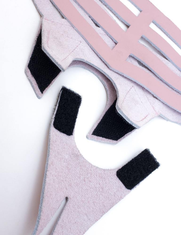 The pink Vanity Strapon Dildo Harness is shown detached against a blank background. The top of the pentagon piece of leather that holds the dildo is attached to the bottom piece with velcro.