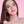 Load image into Gallery viewer, A close-up of a brunette woman with pink makeup is shown in front of a pink background. She wears the Stupid Cute O-Ring Leather BDSM Choker. The choker is made of a thin strip of light pink leather with an O-ring in the center.
