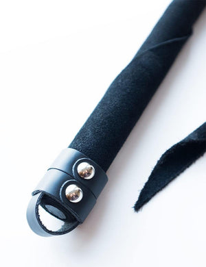 A close-up of the handle of the Black Suede Dragon Tail Whip is shown against a blank background. There is a small leather loop at the base of the handle.