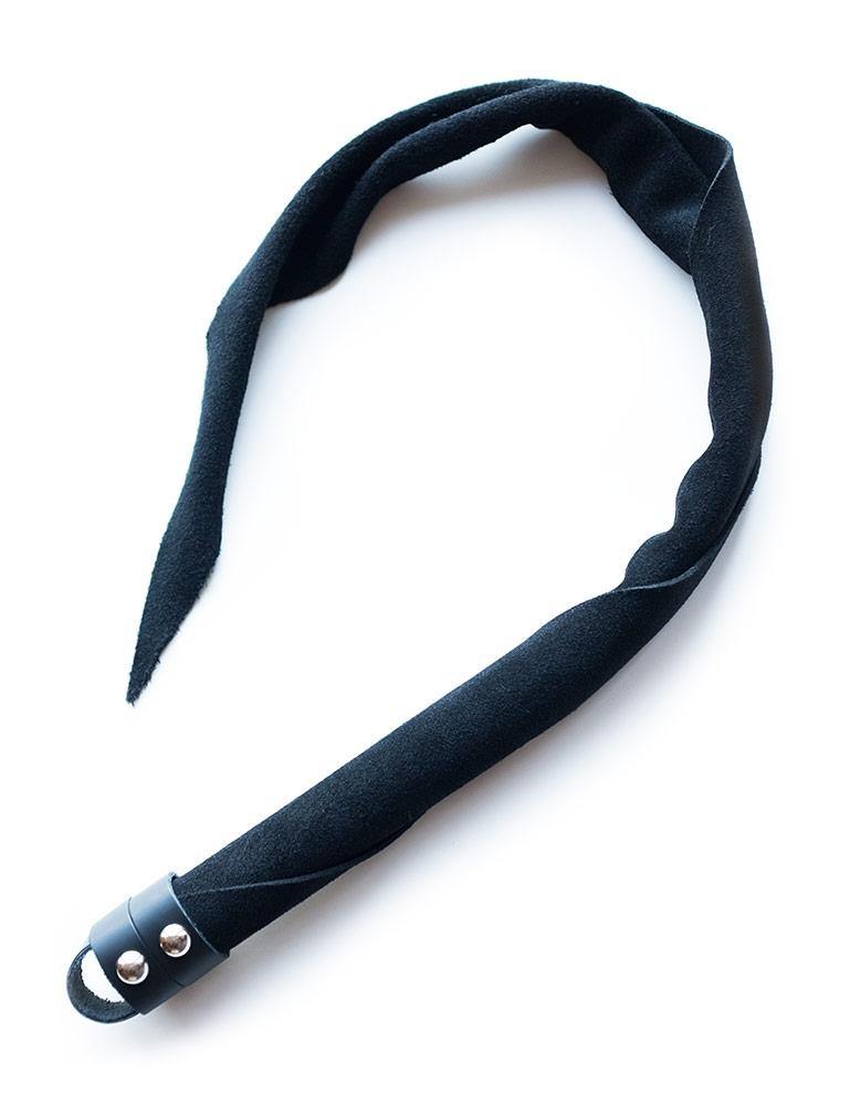 The Black Suede Dragon Tail Whip is shown against a blank background. The suede is wrapped around itself in a tight cylinder at the handle, which loosens towards the top and comes to a point. 