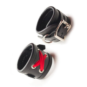 The Red Laced Leather Wrist Cuffs are shown against a blank background. One of the cuffs is turned to show the red lacing on the front, and the other is turned to show the adjustable strap, lockable buckle closure, and D-ring.
