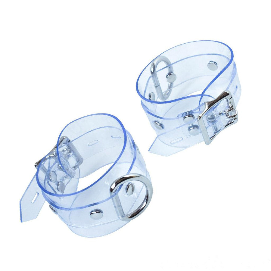 The Clear CTRL Clear Vinyl Wrist Cuffs are shown against a blank background. The cuffs are completely transparent with metal hardware. They each have a lockable buckle with an adjustable strap and a D-ring.