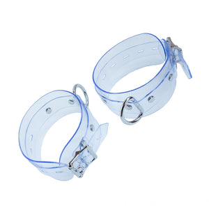 The Clear CTRL Vinyl Ankle Cuffs are shown against a blank background. They are made of a wide piece of transparent PVC with metal hardware. Each cuff has a D-ring and a lockable buckle.