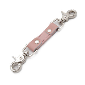 The Stupid Cute Restraint Clip is displayed against a blank background. It is made of light pink leather with silver metal hardware.