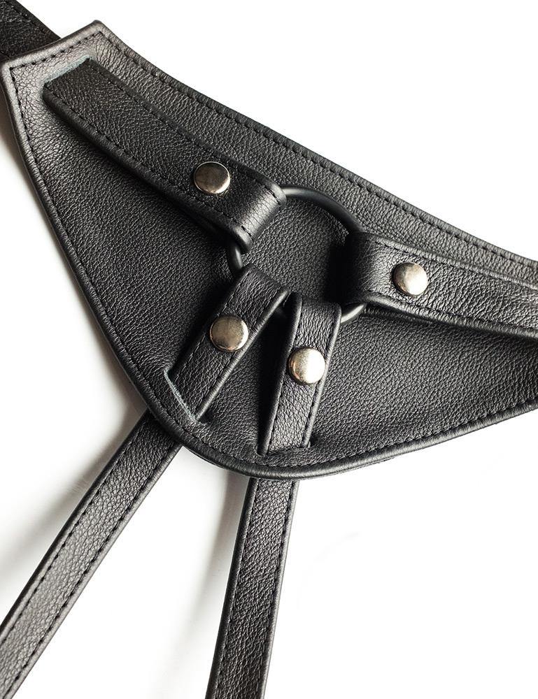 A close-up of the front piece of The Full Curves Leather Strap-on Harness in black is displayed against a blank background. 