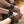 Load image into Gallery viewer, A closeup is shown of a woman’s feet, which are perched on the edge of a dark rattan chair. She is grabbing her feet and is wearing the Fleece Lined Garment Leather Wrist Cuffs and matching ankle cuffs.
