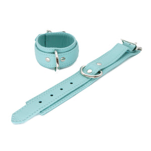 A pair of Zoë Ligon x The Stockroom Limited Edition Mint Green Wrist Cuffs is shown against a blank background, one buckled and one unbuckled. The restraints have an adjustable strap and a metal buckle.