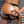 Load image into Gallery viewer, A close-up of a man’s bare butt in a jockstrap is shown with someone holding the Leather Wrapped Round Wood Spanking Paddle against it.
