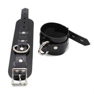 One buckled Stockroom Black PVC Wrist Cuff is shown next to one unbuckled wrist cuff against a blank background.