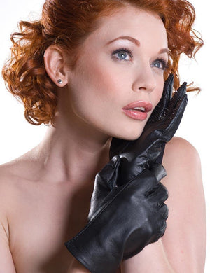 A topless woman with short, curly red hair is shown looking upward against a blank background. She is wearing the Vampire Gloves and cups her face with one hand while the other holds her wrist.