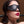Load image into Gallery viewer, A close-up of a brunette woman with red lipstick wearing the black, faux-leather Kinklab Padded Blindfold is shown.
