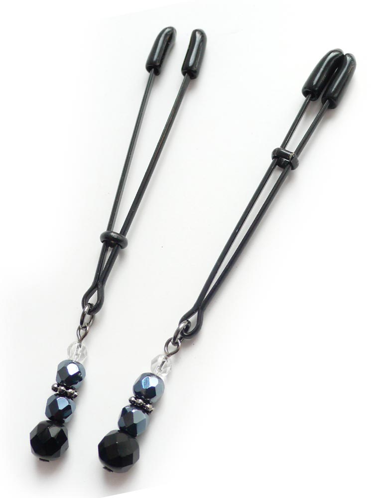 A pair of black Beaded Nipple Clamps are displayed against a blank background. They are adjustable tweezer-style clamps with rubber tips with a decorative string of beads dangling from the bottom of each clamp.
