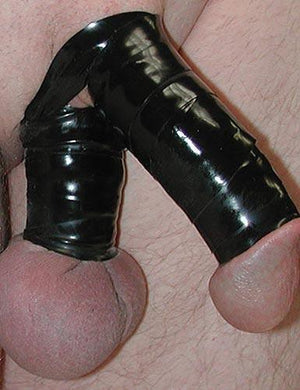 A close-up of a penis is shown with the shaft and top of the scrotum wrapped tightly in black Latex Bondage Strips.