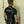 Load image into Gallery viewer, A brunette man poses in front of a white wall, facing away from the camera. He wears the Uniform Shirt from Syren Latex in black, matching pants, and arm gauntlets. 
