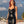 Load image into Gallery viewer, A woman with pink hair poses on a rooftop with a cloudy sky and the Los Angeles skyline behind her. She wears the Latex Halter Dress from Syren Latex in black.
